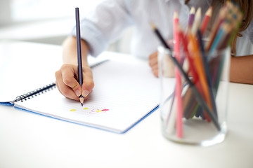 Image showing girl drawing with color pencil pen in notebook