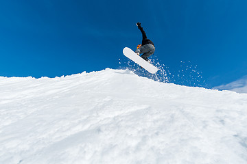 Image showing Snowboarder jumping against blue sky