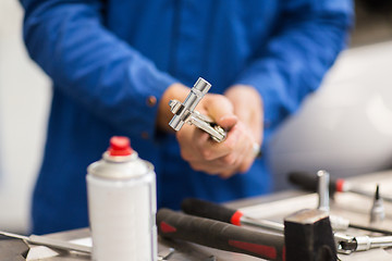 Image showing mechanic man with wrench repairing car at workshop