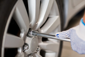 Image showing mechanic with screwdriver changing car tire