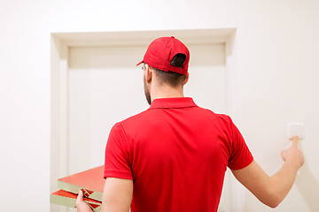 Image showing delivery man with pizza boxes ringing doorbell