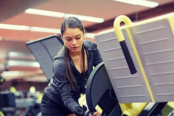 Image showing young woman adjusting leg press machine in gym