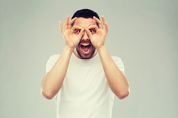 Image showing man making finger glasses over gray background