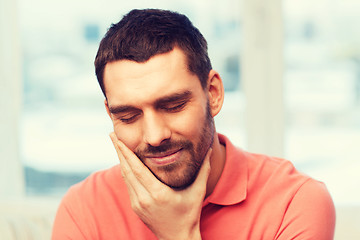 Image showing unhappy man suffering toothache at home