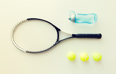 Image showing close up of tennis racket with balls and bottle
