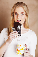 Image showing young cute blond girl eating chocolate and drinking coffee close