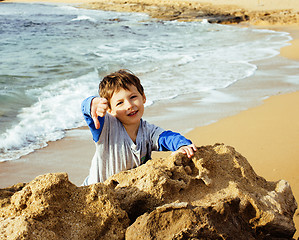 Image showing little cute boy on sea coast thumbs up playing with rocks