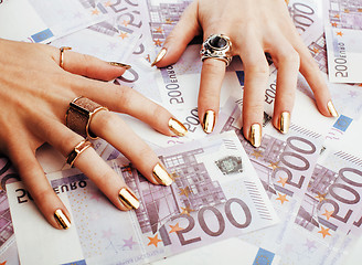 Image showing hands of rich woman with golden manicure and many jewelry rings 