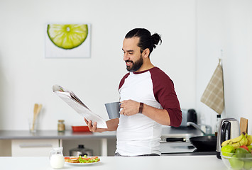 Image showing man reading newspaper and eating at home kitchen