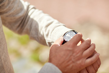 Image showing senior man checking time on wristwatch outdoors