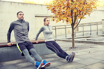 Image showing couple doing triceps dip on city street bench