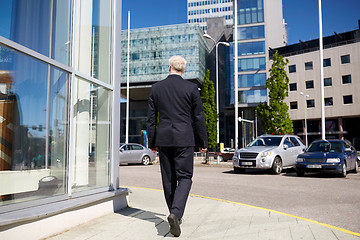 Image showing senior businessman walking along city street