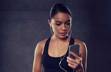 Image showing woman with smartphone and earphones in gym