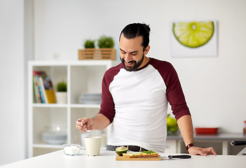 Image showing man adding sugar to cup for breakfast at home