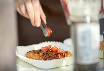 Image showing close up of cook hand adding strawberry to waffle