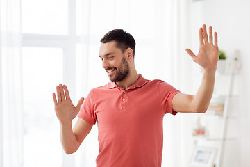 Image showing happy man touching something imaginary at home