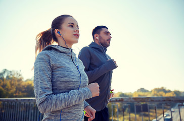 Image showing happy couple with earphones running outdoors