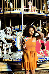 Image showing cool real teenage girl with candy near carousels at amusement pa