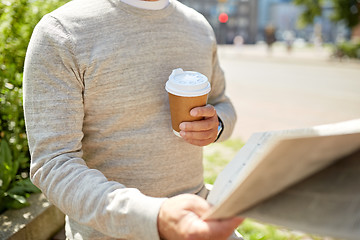 Image showing senior man with coffee reading newspaper outdoors