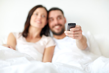 Image showing happy couple lying in bed at home and watching tv