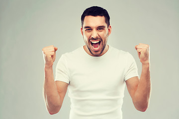 Image showing young man celebrating victory over gray