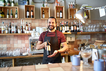 Image showing happy man or waiter with bottle of red wine at bar