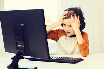 Image showing terrified boy with computer and headphones at home