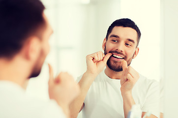 Image showing man with dental floss cleaning teeth at bathroom