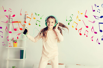 Image showing girl jumping on bed with smartphone and headphones