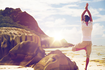 Image showing man meditating in yoga tree pose over beach