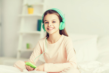 Image showing girl sitting on bed with smartphone and headphones