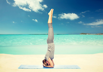 Image showing woman making yoga in headstand pose on beach 