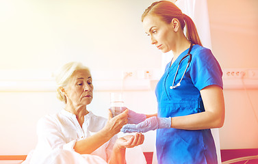 Image showing nurse giving medicine to senior woman at hospital