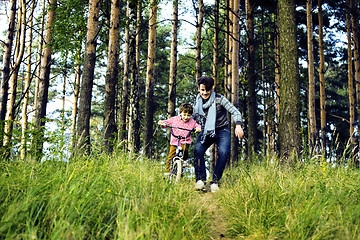 Image showing father learning his son to ride on bicycle outside, real happy f