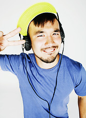 Image showing young asian man in hat and headphones listening music on white b