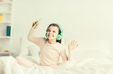 Image showing girl sitting on bed with smartphone and headphones