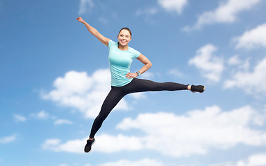 Image showing happy sporty young woman jumping in blue sky