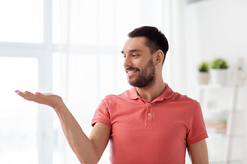 Image showing happy man holding something imaginary at home