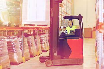 Image showing man with tablet pc operating forklift at warehouse