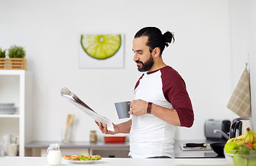 Image showing man reading newspaper and eating at home kitchen