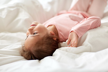 Image showing happy little girl lying in bed at home