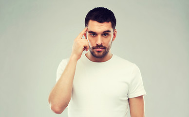 Image showing man with finger at temple over gray background