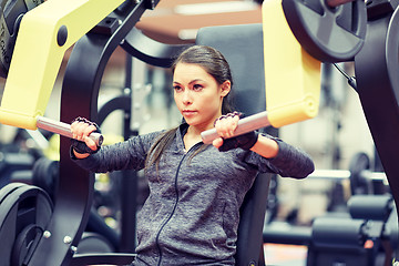 Image showing woman flexing muscles on chest press gym machine 