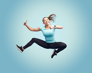 Image showing happy smiling sporty young woman jumping in air