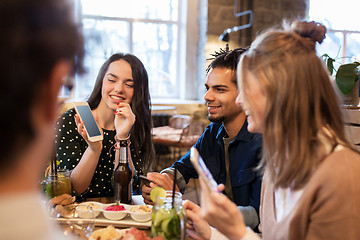 Image showing friends with smartphones and food at bar or cafe