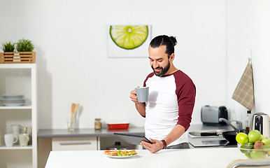 Image showing man with tablet pc eating at home kitchen