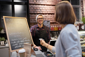 Image showing barman and woman paying with credit card at cafe