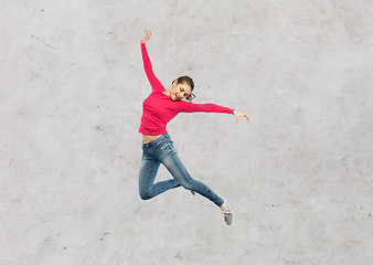 Image showing happy young woman jumping in air or dancing