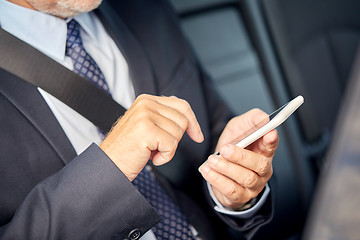 Image showing senior businessman texting on smartphone in car