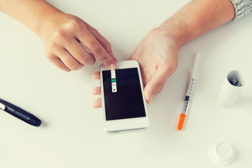 Image showing close up of woman with smartphone doing blood test